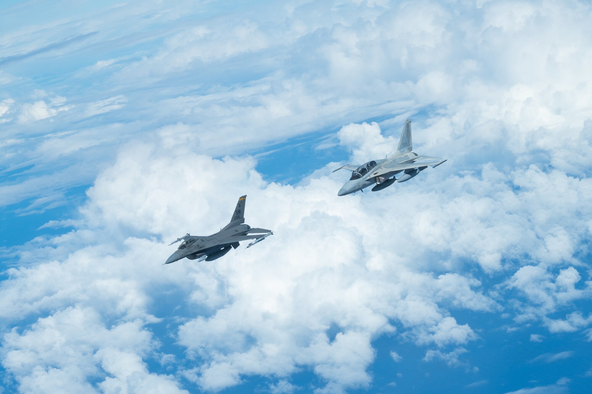 Bilateral aircraft fly in formation over the ocean.