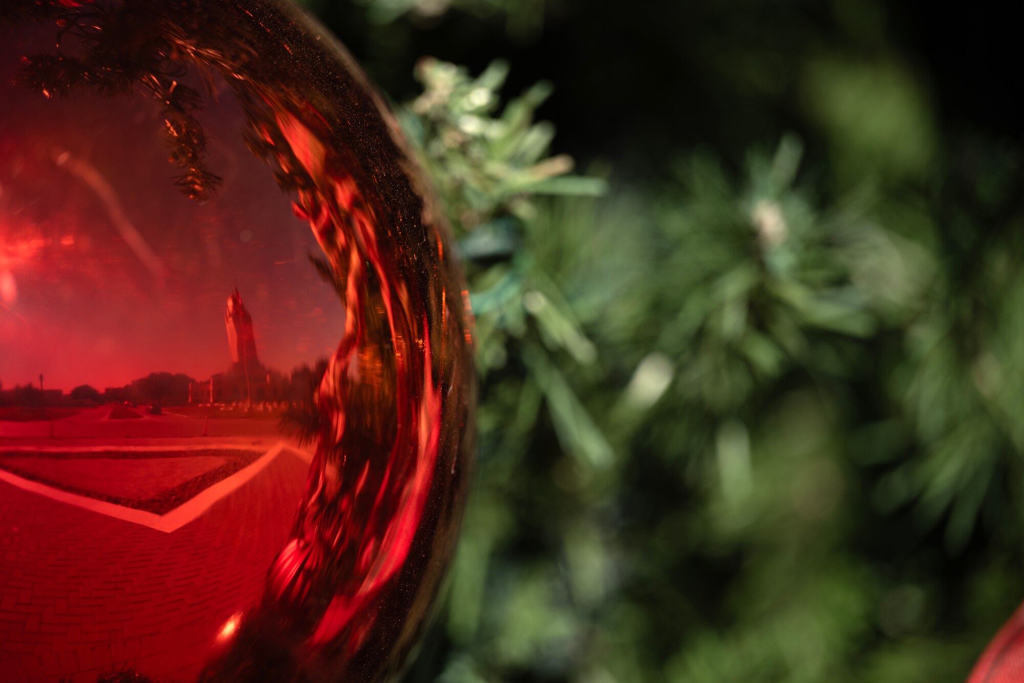 red holiday ball in front of green tree