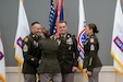 Soldier in dress uniform accepts Recruiting Brigade flag with streamers from another soldier while two others look on.