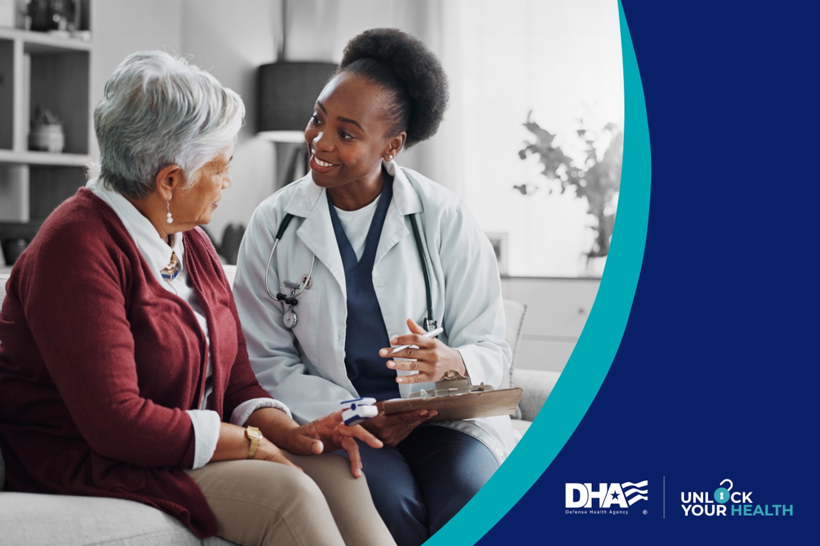 Doctor wearing white coat sits on a couch next to an elderly patient and shows her a clipboard.