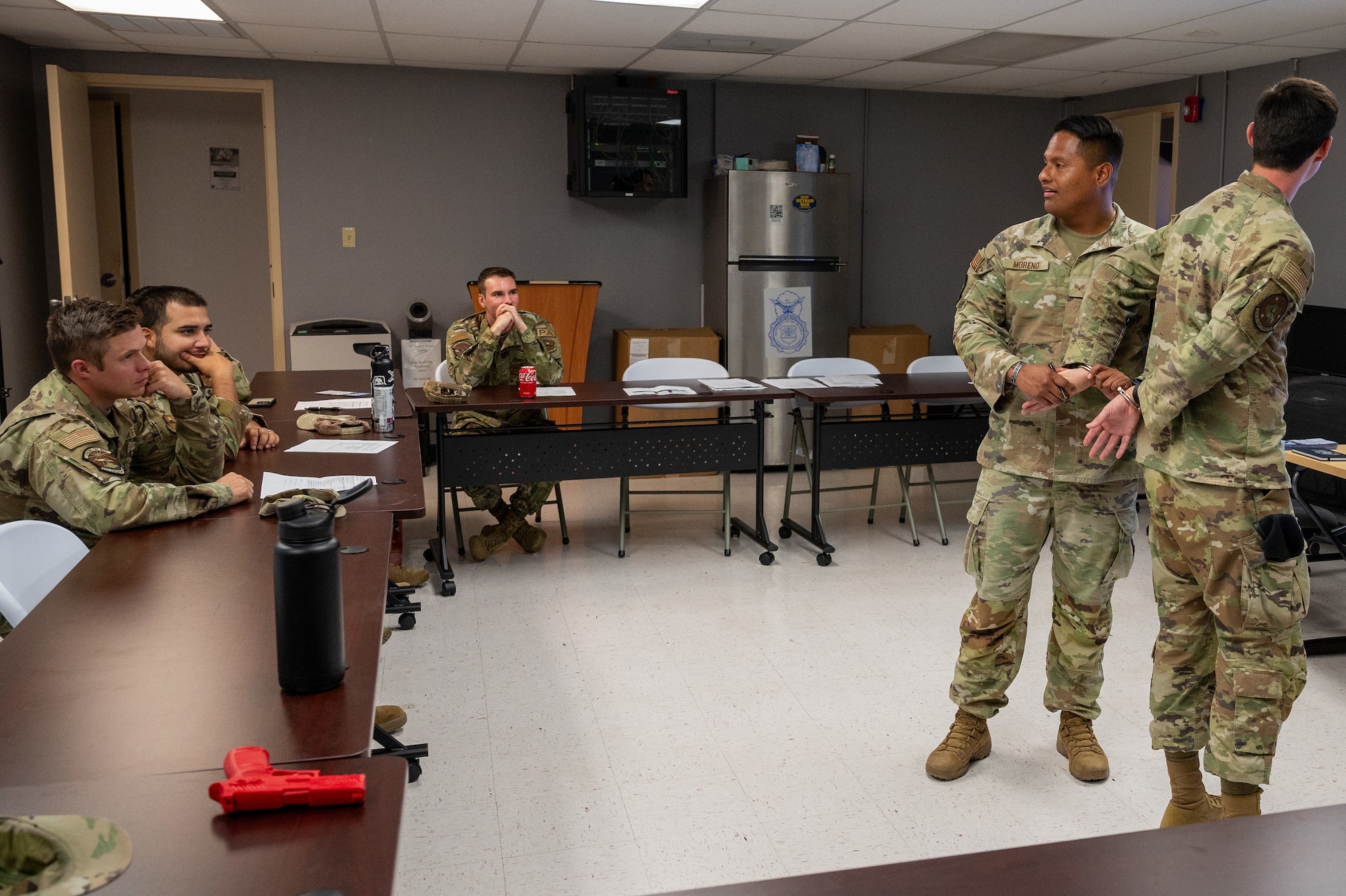 U.S. Air Force Senior Airman Morento, 47th Security Forces Squadron trainer, demonstrates the proper procedure to handcuff a person who is detained to security forces augmentee trainees at Laughlin Air Force Base, Texas, August 21, 2024.  The 47th SFS is training security forces augmentees to enhance mission capabilities, providing extra personnel in case of emergencies. (U.S. Air Force photo by Staff Sgt. Nicholas Larsen)