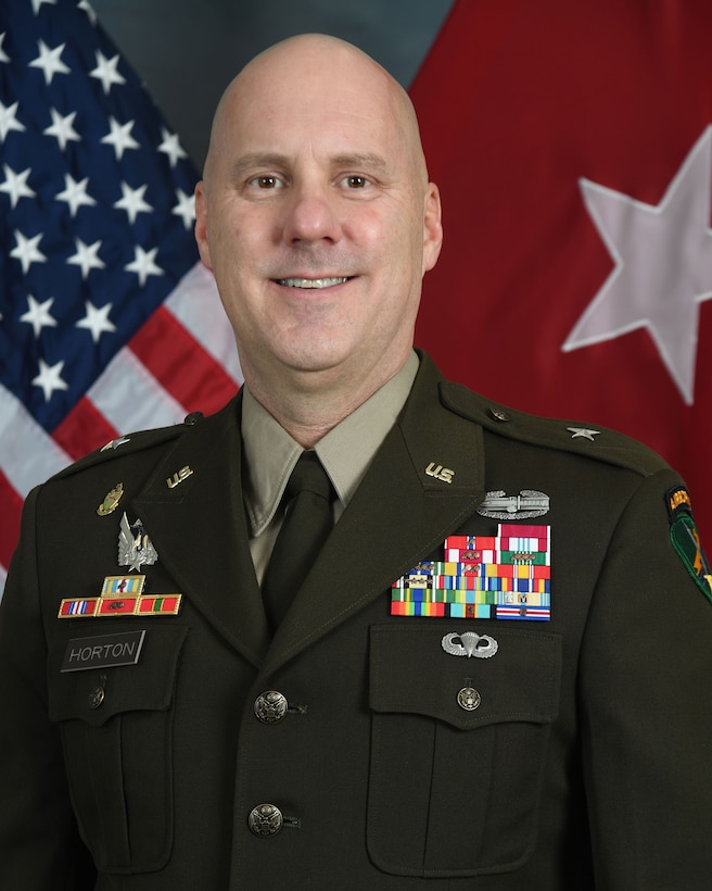 Brig. Gen. Brian Horton, commanding general, 351st Civil Affairs Command in his dress uniform posed before the U.S. flag and general officer one-star flag for his command photo.