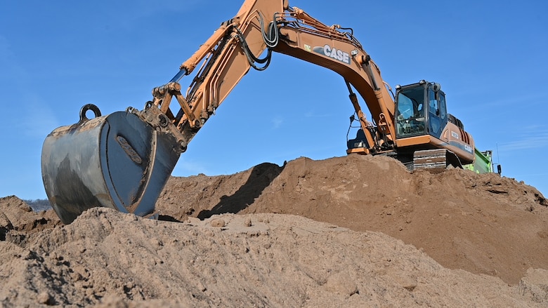 A yellow excavator scoops sand.