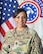 Female Soldier in uniform smiles while standing in front of United States and Army Recruiting Flags