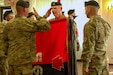 A longstanding Army tradition, the incoming Joint Multinational Training Group – Ukraine commander, Col. Christopher Costello, unfurls the brigade colors during a transfer of authority ceremony at Grafenwoehr, Germany, Oct. 1, 2024. Headquarters and Headquarters Company, 56th Stryker Brigade Combat Team, Pennsylvania National Guard assumes authority of the JMTG-U mission from Task Force Thunder, 155th Armored Brigade Combat Team, Mississippi National Guard. JMTG-U’s training of members of the Armed Forces of Ukraine helps develop the skills of Ukrainian units to conduct joint maneuver and combined arms operations and builds on specialized, individual, and collective training facilitated by U.S. Allies and partners. (U.S. Army National Guard photo by Capt. Leanne Demboski)