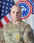 Army Recruiting Sergeant Major in uniform poses in front of United States and Army Recruiting flags for official command photo