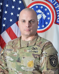 Army Recruiting Sergeant Major in uniform poses in front of United States and Army Recruiting flags for official command photo