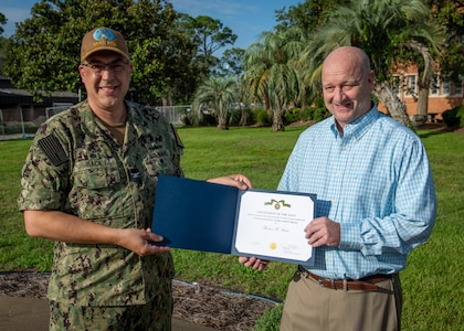 (left) Capt. David Back, Naval Surface Warfare Center Panama City Division commanding officer, presents Project Management Competency Lead Tommy Hosea with the Navy Civilian Service Achievement Medal for leading wartime readiness efforts during the Naval Sea Systems Command 2024 exercise, July 26. The 21-day, large-scale, multi-organizational event focused on wartime readiness to support the fleet. (U.S. Navy photo by Anthony Powers)