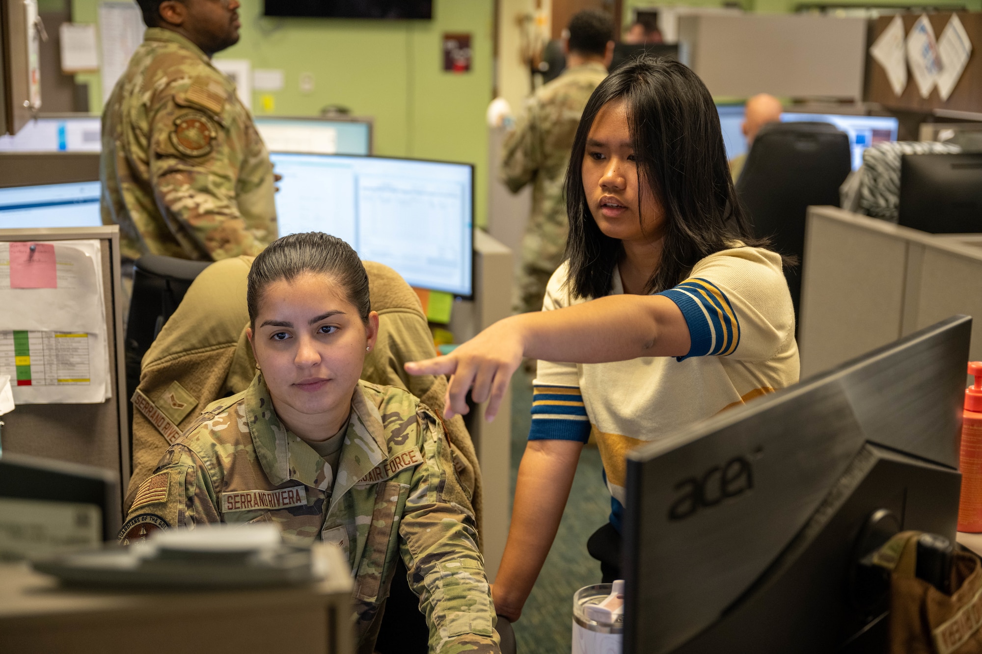 Airman and civilian work on financial duties on a desktop.