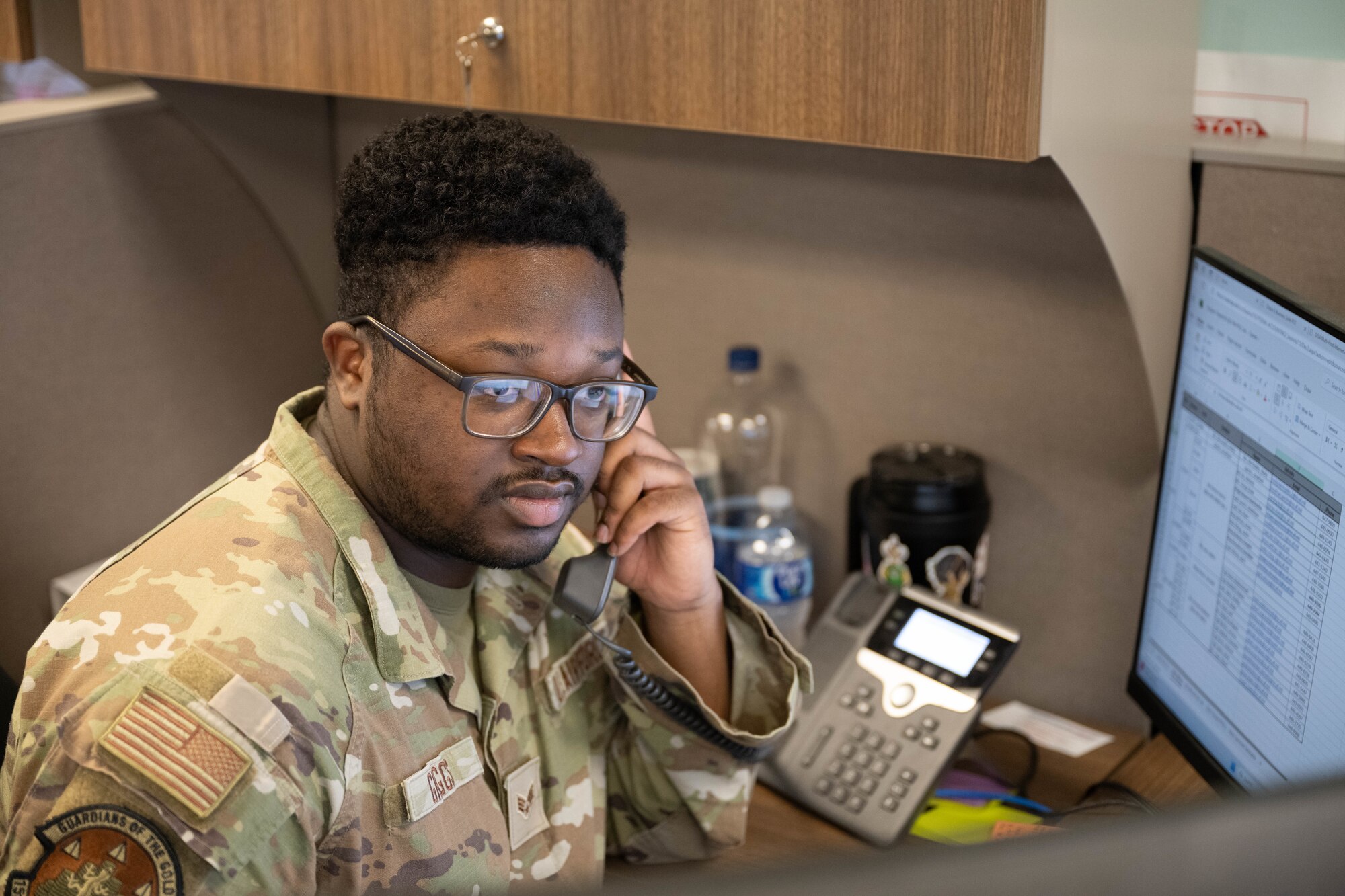 An Airman talks on a phone in an office.