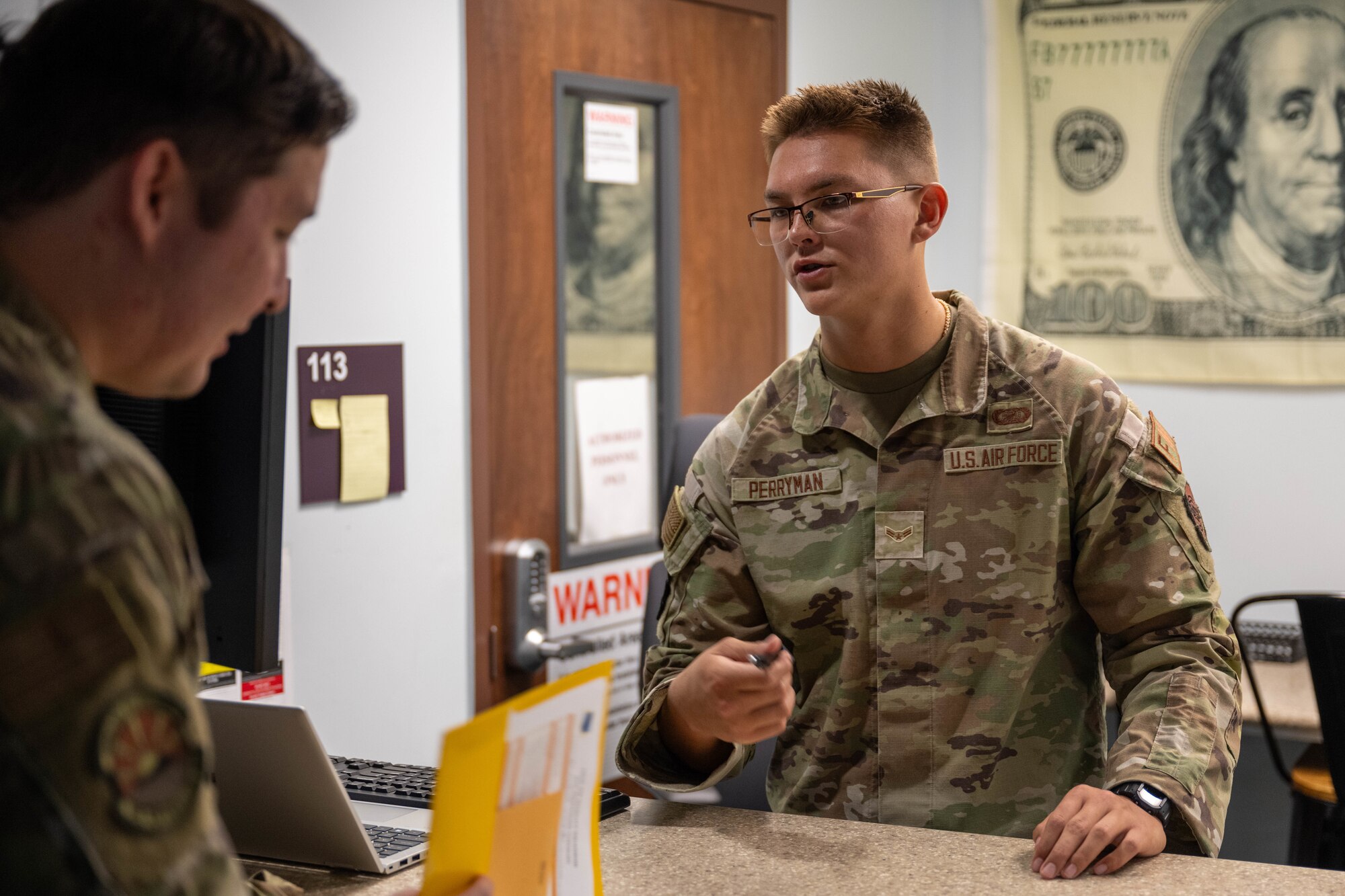 A finance Airman speaks to a customer from behind a desk.