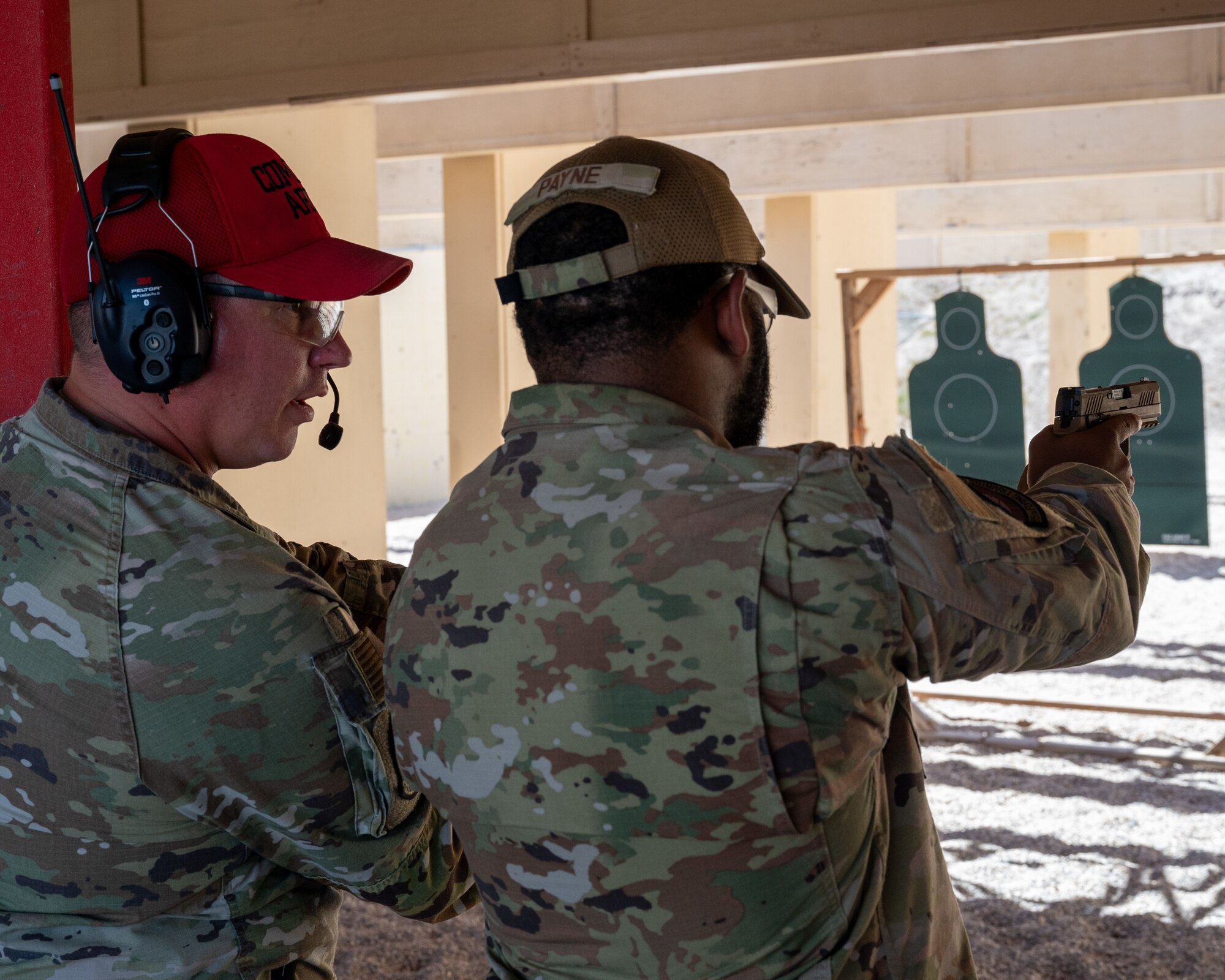 U.S. Air Force Tech. Sgt. Casey Blickenstaff, left, 47th Security Forces Squadron combat arms instructor, instructs Senior Airman Ari Payne, 87th Flying Training Squadron security forces augmentee, in the operation of an M-18 pistol at Laughlin Air Force Base, Texas, Aug. 21, 2024. During qualification Airmen shot the M-18 and M-4, qualifing them to carry them when on duty as augmentees. (U.S. Air Force photo by Staff Sgt. Nicholas Larsen)