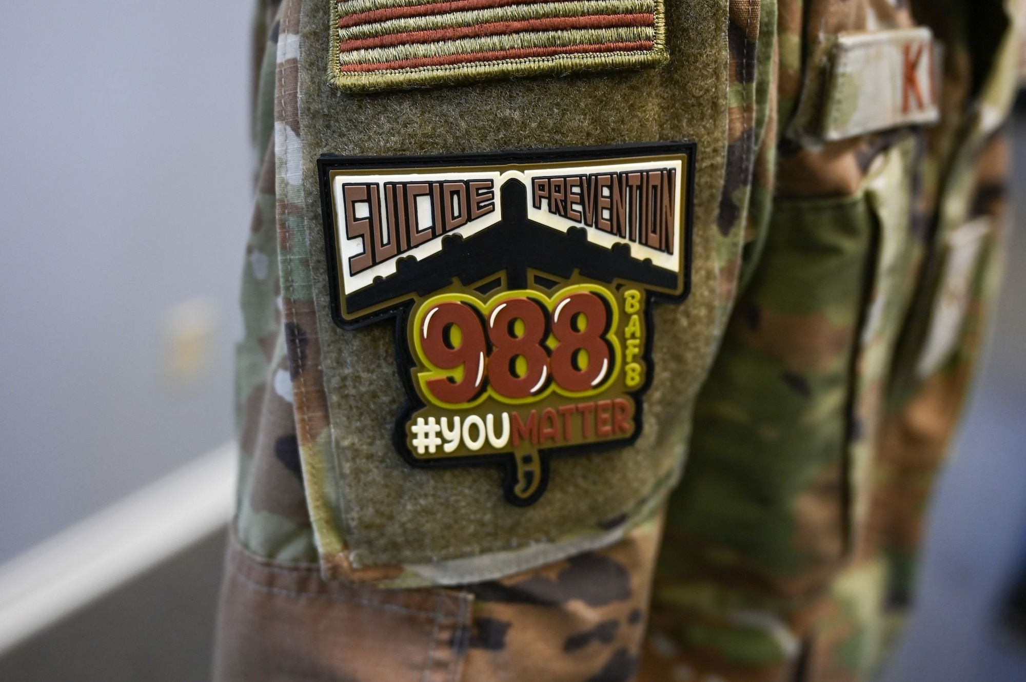 An OCP morale patch showing 988 is worn by an Airman in OCPs