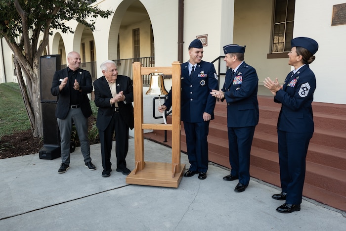 military members stand around bell.