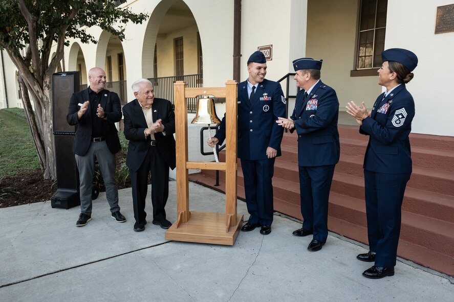 military members stand around bell.