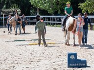 Families and Sand and Spur Riding Club members guide horses around a field.