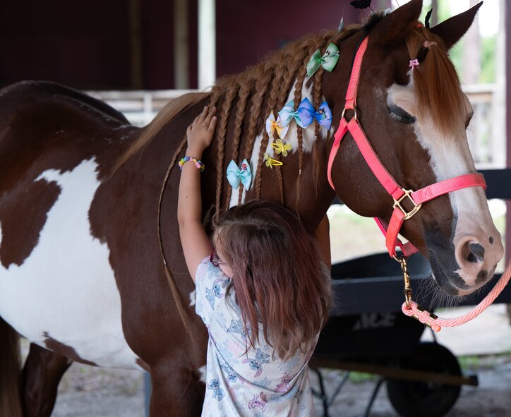 A young girl hugs a horse around its neck.