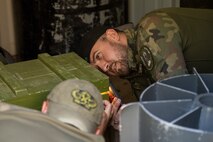 Polish Land Forces Cpl. Nikodem Stelmaszek, right, and Warrant Officer Blazej Basinski, 16th Airfield Renovation Battalion explosive ordnance disposal (EOD) technicians, inspect a munitions box for booby traps.
