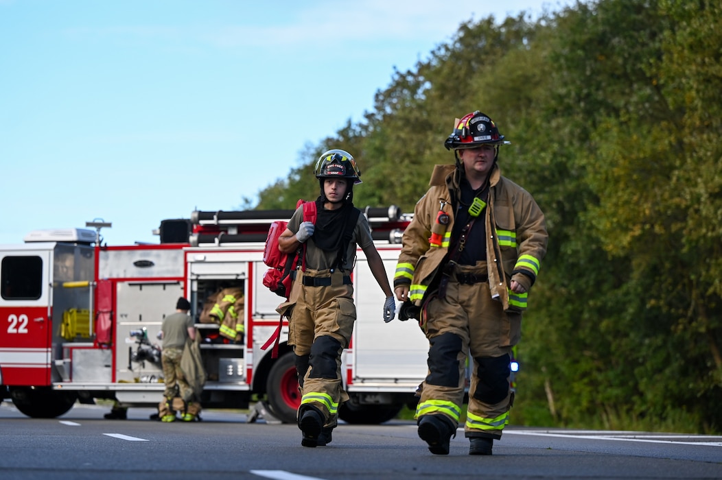 Firefighters walk to a simulated scene of a burning school bus