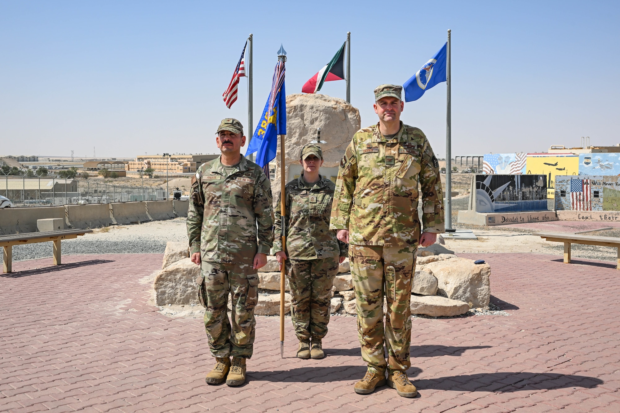 Three service members stand outside to recognize a change of leadership.