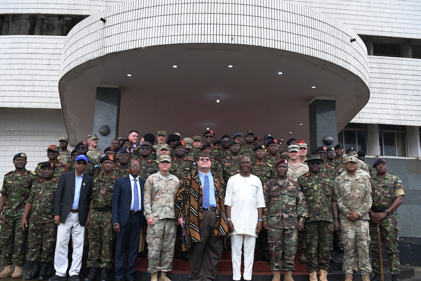 A group of service members and civilians from the U.S. and Sierra Leone pose for a photograph outside a building.