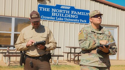 Sgt. Donald Underwood, an unmanned aerial systems operator with Delta Company, 545th Brigade Engineer Battalion, 45th Infantry Brigade Combat Team, Oklahoma Army National Guard, operates a UAS with Trooper Adam Post, Oklahoma Highway Patrol, during a multi-agency wildland firefighting unmanned aerial systems integration exercise at Crowder Lake near Weatherford, Oklahoma, Sept. 25-26. The exercise brought the Oklahoma National Guard, state and local agencies and several private UAS companies together to develop a common operating picture, ensuring all public safety teams have a shared view of a multi-agency response to events like wildland firefighting. (Oklahoma National Guard photo by Staff Sgt. Reece Heck)