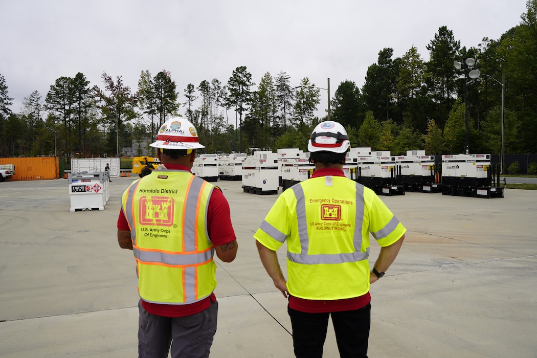 Two USACE Employees look at a group of generators that are positioned to be deployed to areas hit by Hurricane Helene in North Carolina.