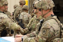 Two Soldiers look down at a map while planning a convoy.