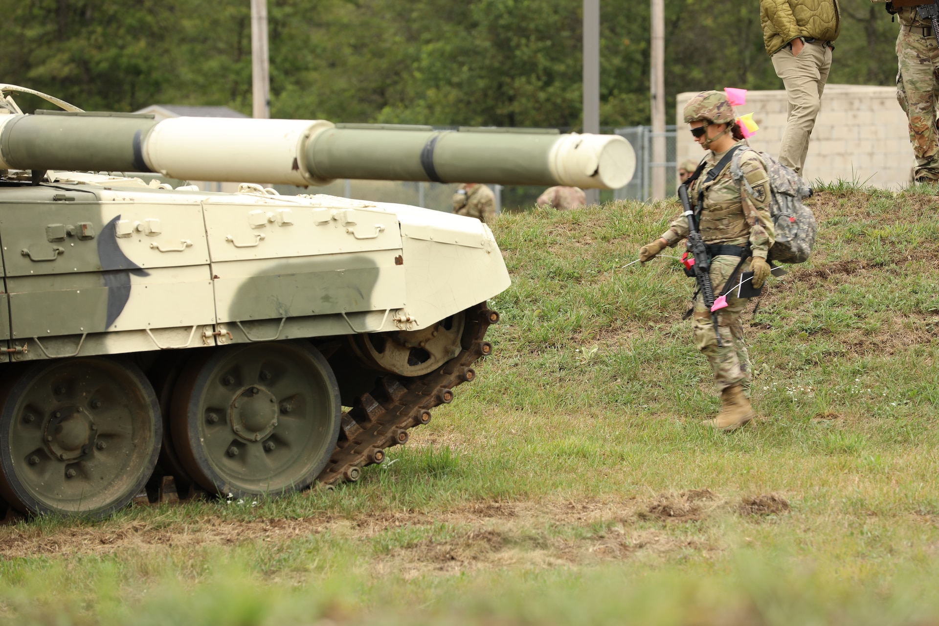 A Soldier carrying a pink marking flag approaches a T-72 main battle tank.