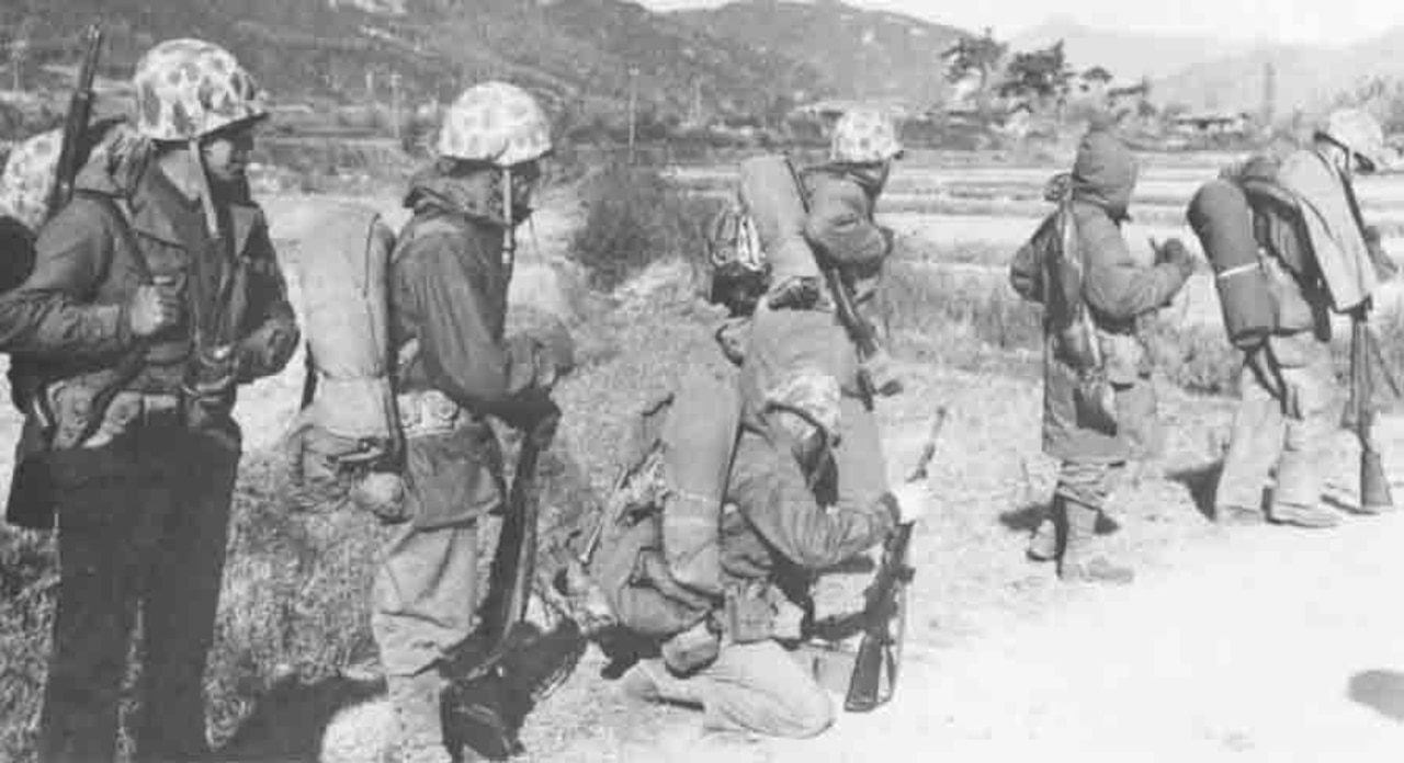 Men in cold-weather gear and helmets march in order.