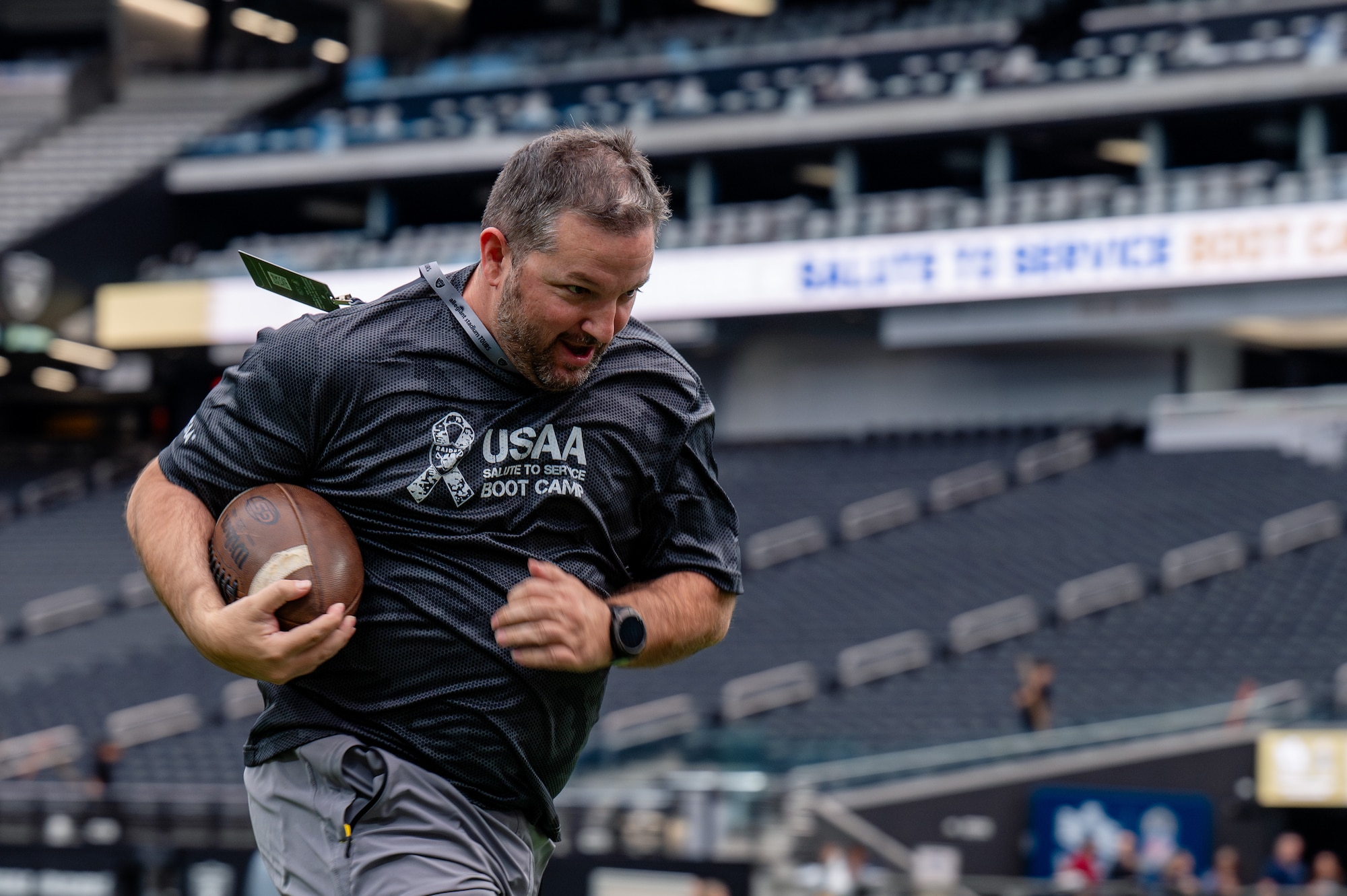 An Airman runs with a football in his hand.