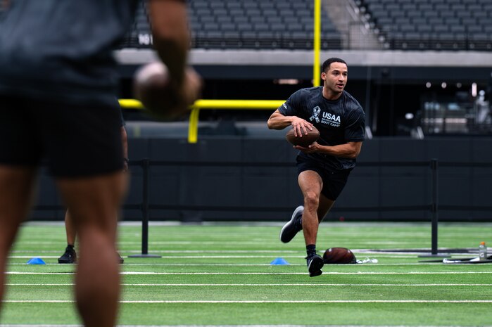 An Airman runs with a football in his hand.