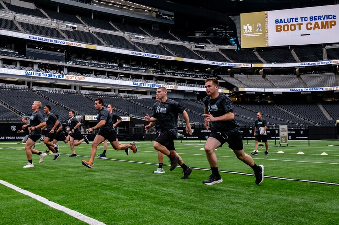 A group of Airmen run across a football field.