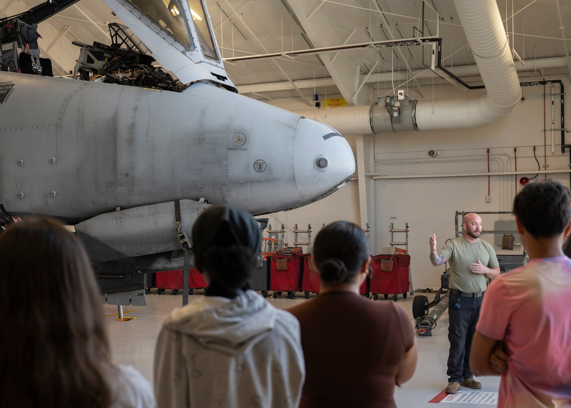 A U.S. Airman speaks to  Air Force Junior Reserve Officer Training Corps students in front of an A-10C Thunderbolt II aircraft.