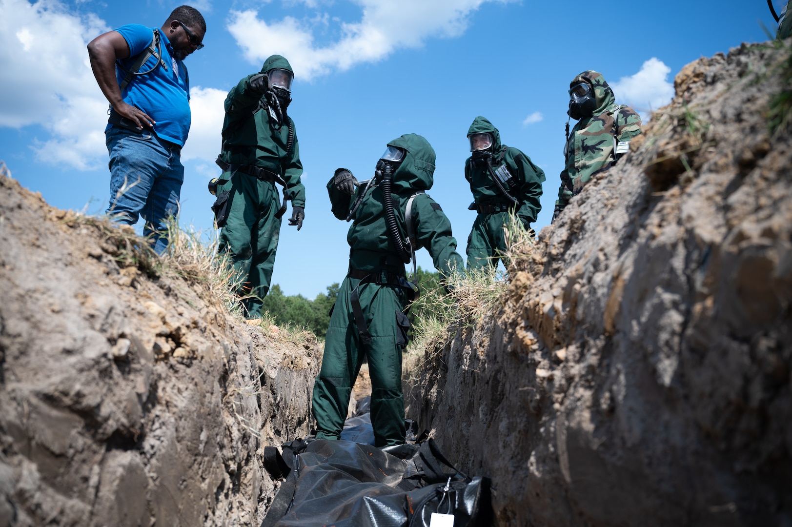 Fredrick Kennebrew, left, a mortuary affairs evaluator assigned to the Joint Test and Evaluation Program, observes fatality search and recovery team Airmen and mortuary affairs Soldiers as they practice temporary interment of simulated contaminated human remains during an exercise at Fort Gregg-Adams, Virginia, Sept. 11, 2024. The exercise was part of a quick reaction test to refine the techniques, tactics and procedures for managing and caring for the remains of fallen service members.