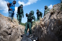 Fredrick Kennebrew, left, a mortuary affairs evaluator assigned to the Joint Test and Evaluation Program, observes fatality search and recovery team Airmen and mortuary affairs Soldiers as they practice temporary interment of simulated contaminated human remains during an exercise at Fort Gregg-Adams, Virginia, Sept. 11, 2024. The exercise was part of a quick reaction test to refine the techniques, tactics and procedures for managing and caring for the remains of fallen service members.