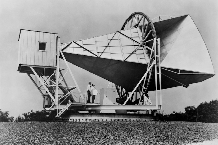 Two people stand below an antenna.