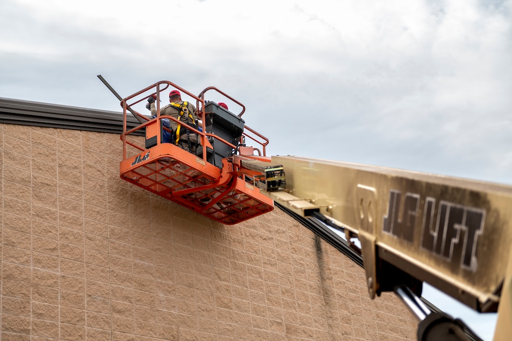 People performing construction on a mechanical lift