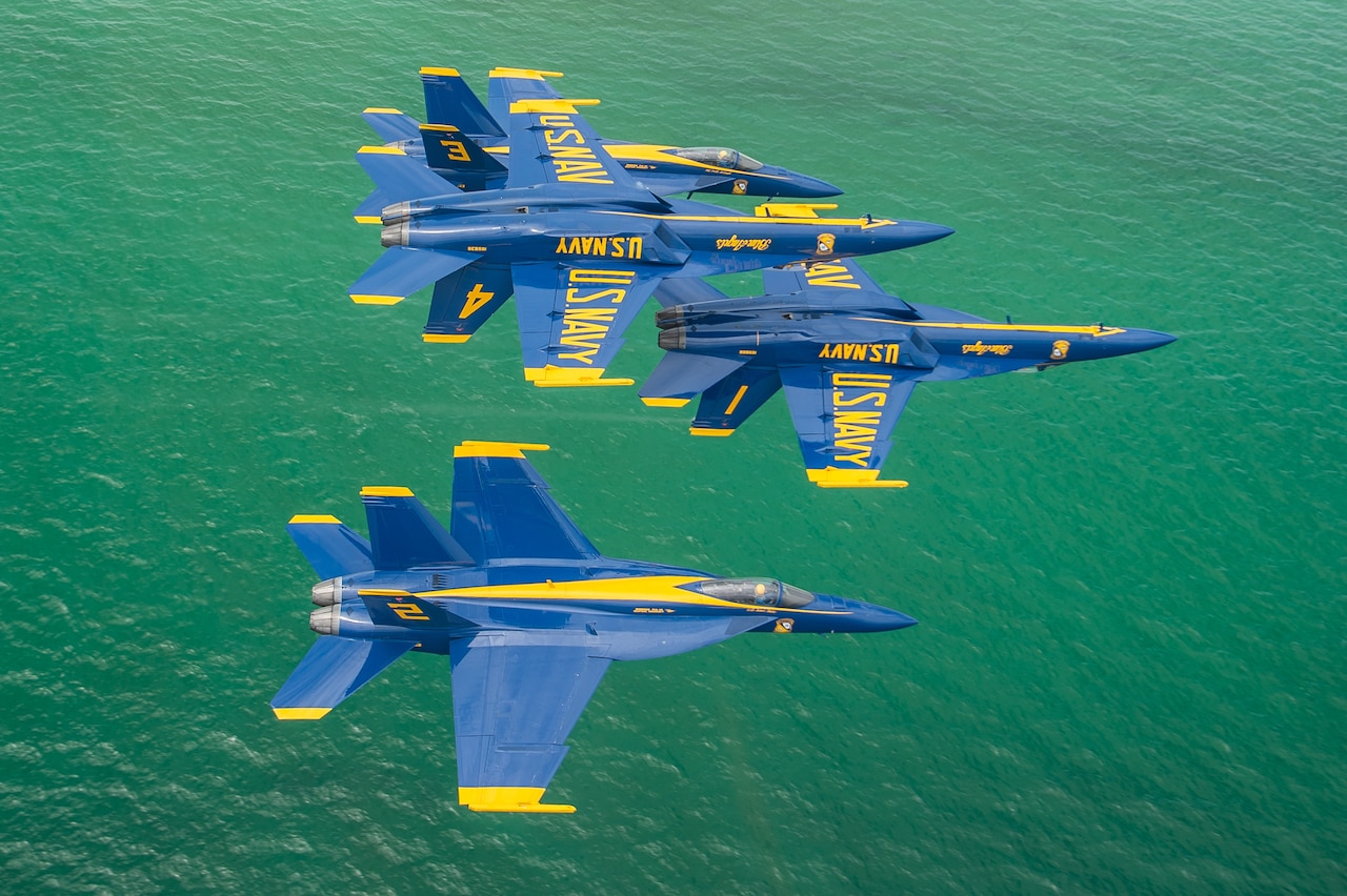 As seen from above the Blue Angels perform the double farvel maneuver over a green sea.