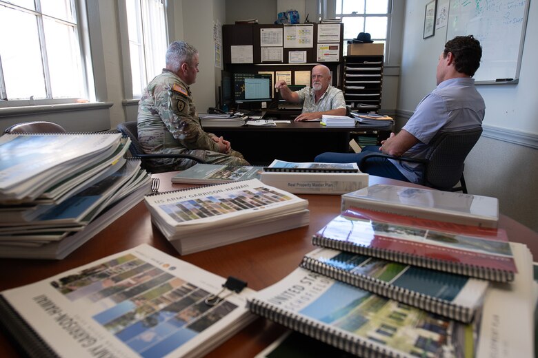 Col. Calvin Kroeger, left, commander of the U.S. Army Corps of Engineers' Fort Worth District, and Joey Ball, right, the chief of Master Planning from the Fort Worth District's Regional Planning and Environmental Center, meet with Tom Burton, center, the chief of Master Planning at the Department of Public Works, U.S. Army Garrison - Hawaii, to discuss the crucial planning support RPEC has provided USAG-H. In foreground are just some of the projects that RPEC has supported USAG-H with over the past five years.
