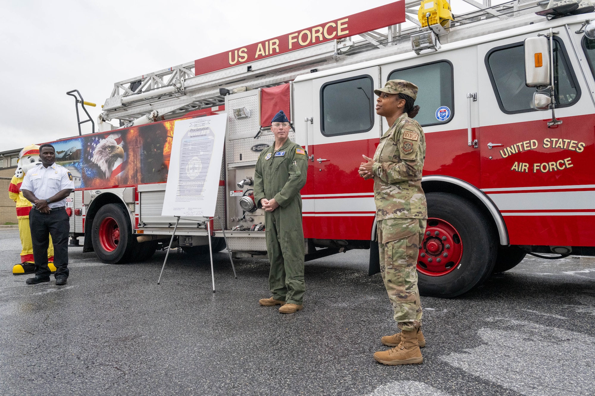 U.S. Air Force Col. Chris McDonald, center, 436th Airlift Wing commander, and Chief Master Sgt. Carolyn Russell, right, 436th AW command chief, speak to Airmen and firefighters of the 436th Civil Engineer Squadron prior to signing the 2024 Fire Prevention Week proclamation, at Dover Air Force Base, Delaware, Oct. 2, 2024. During Fire Prevention Week, the 436th CES firefighters provide the Dover community with lifesaving education in an effort to decrease fire safety hazards. (U.S. Air Force photo by Mauricio Campino)