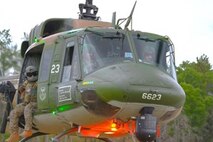 Airman Justin Todd, 54th Helicopter Squadron (54HS) UH-1N Iroquois flight engineer (left), sits by a M-240 while U.S. Air Force Capt. Damon Lappe, 54HS UH-1N Iroquois pilot (center) and U.S. Air Force Capt. Grace Orahood, 54 HS UH-1N Iroquois pilot (right), fly over Camp Ripley, Minnesota, Sept. 24, 2024.The 54 HS coordinated with the 91st Missile Security Operations Squadron to designate simulated targets for Operation Cerberus.