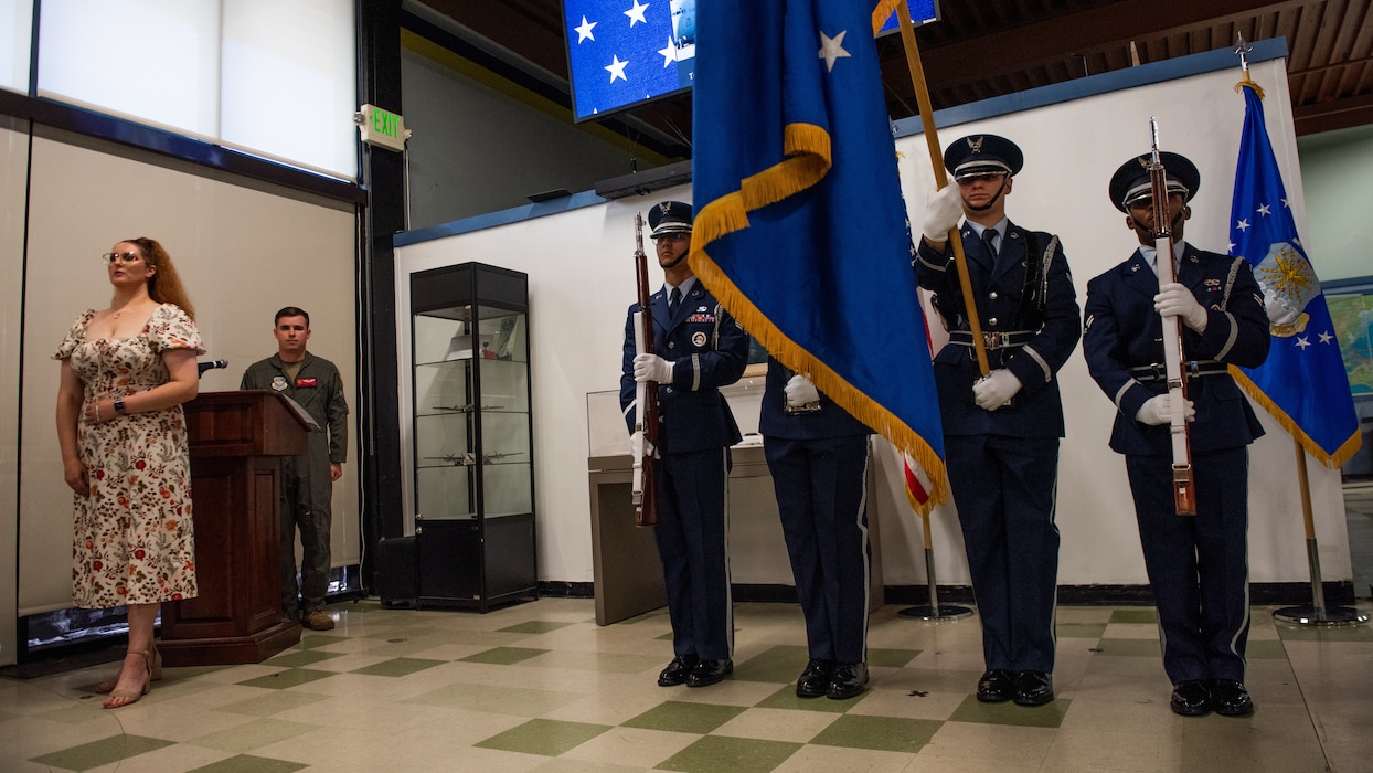 Honor guard presents the colors while a singer performs the national anthem