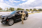 Soldier hands water to a man in a black car