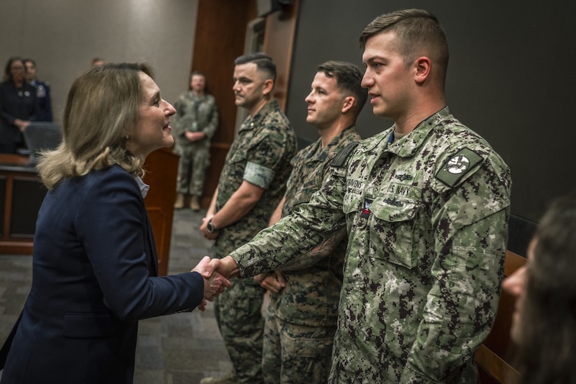 A woman in civilian attire greets a service member in uniform.