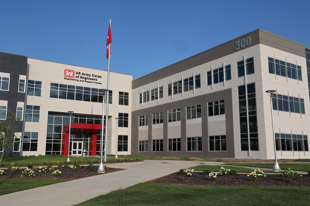 Image of Huntsville Center's three story building with Corps of Engineers flag flying in front.