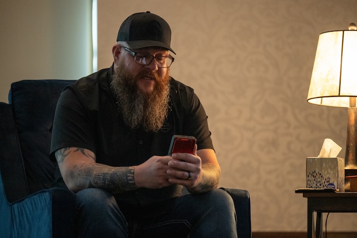 A man reads a letter he wrote to his late brother saved on his cell phone.