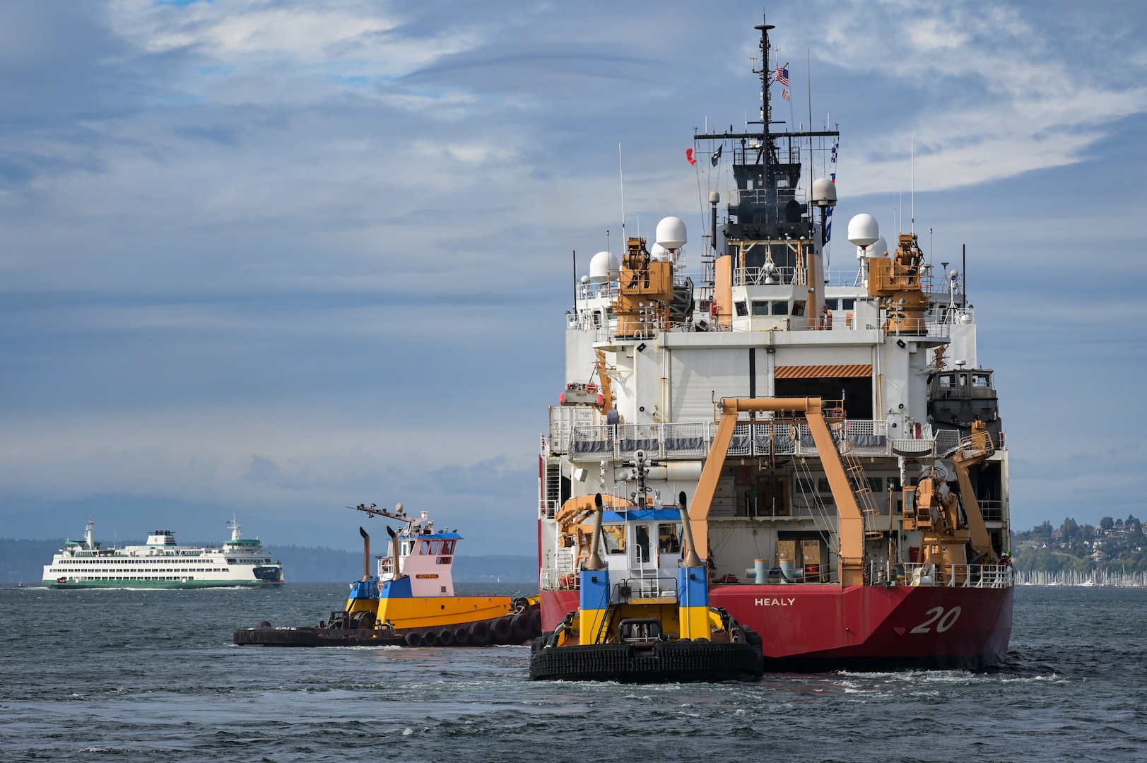 U.S. Coast Guard Cutter Healy (WAGB 20) utilizes assist tugs to back away from the pier after departing Base Seattle, Oct. 1, 2024. Healy is the United States' largest polar icebreaker and the Coast Guard’s only icebreaker designed and equipped with scientific instrumentation by the National Science Foundation to support Arctic research. (U.S. Coast Guard photo by Petty Officer 1st Class Steve Strohmaier)