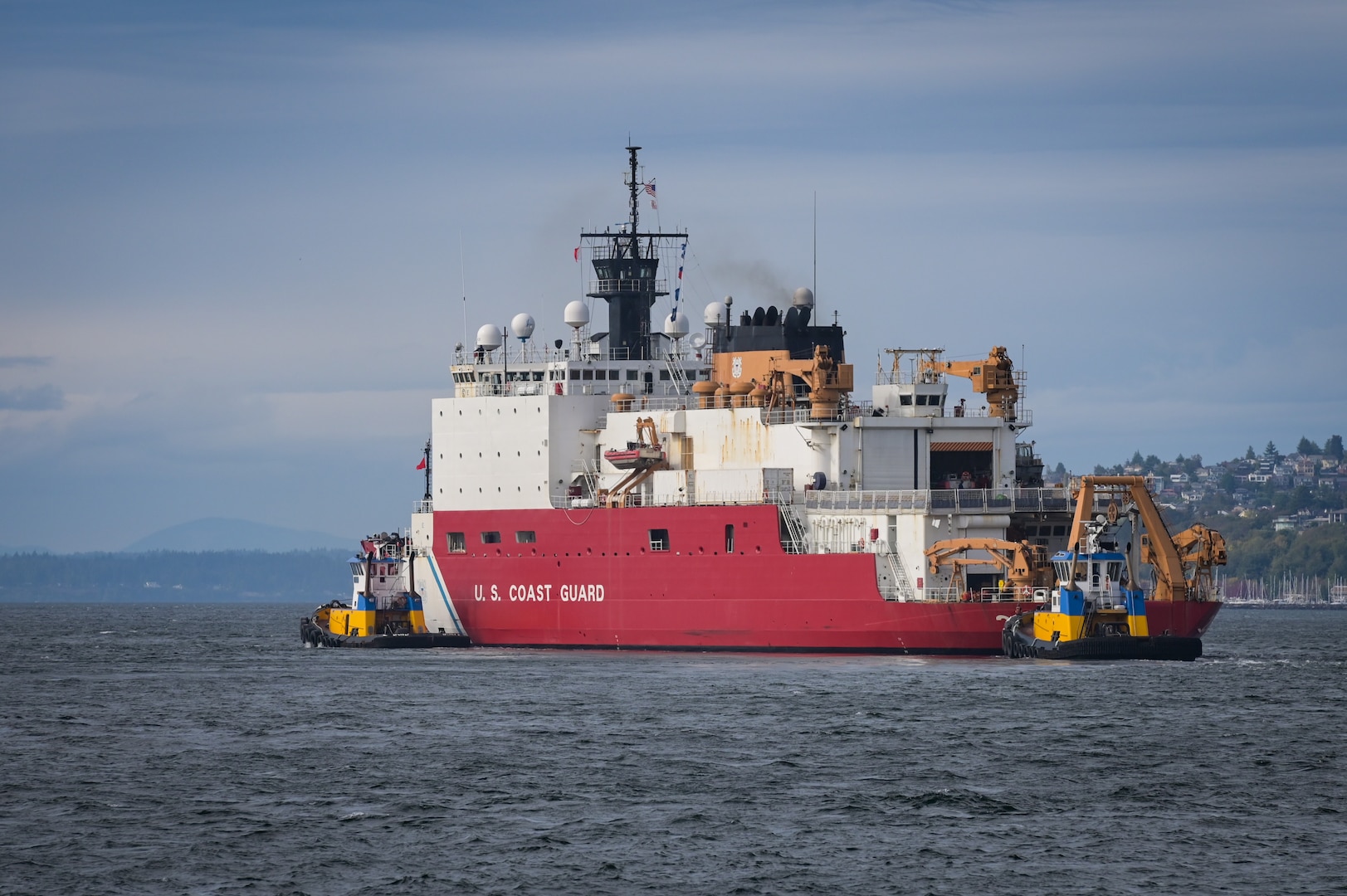 U.S. Coast Guard Cutter Healy (WAGB 20) transits with assist tugs through Elliott Bay near Seattle following its departure from Base Seattle, Oct. 1, 2024. The crew of the Healy are scheduled to resume their scientific mission that was cut short due to an onboard fire in late July. (U.S. Coast Guard photo by Petty Officer 1st Class Steve Strohmaier)