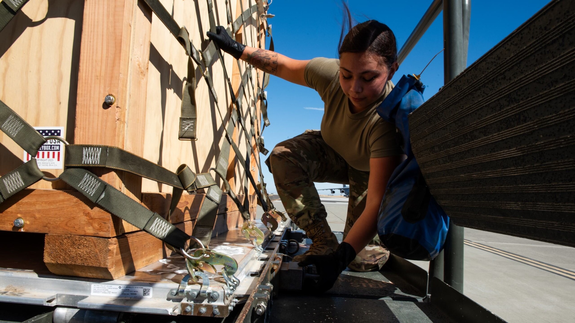 A service member secures a pallet of cargo.